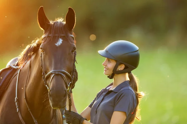 Giovane cavallerizza con il suo cavallo alla luce del tramonto della sera — Foto Stock