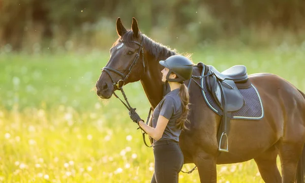 Νεαρή γυναίκα αναβάτης με το άλογο το απόγευμα το φως του ηλιοβασιλέματος — Φωτογραφία Αρχείου
