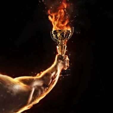 Kaslı adam kol siyah arka plan üzerine yanan trophy Kupası holding