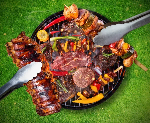 Вид зверху на свіже м'ясо та овочі на грилі, розміщеному на траві — стокове фото