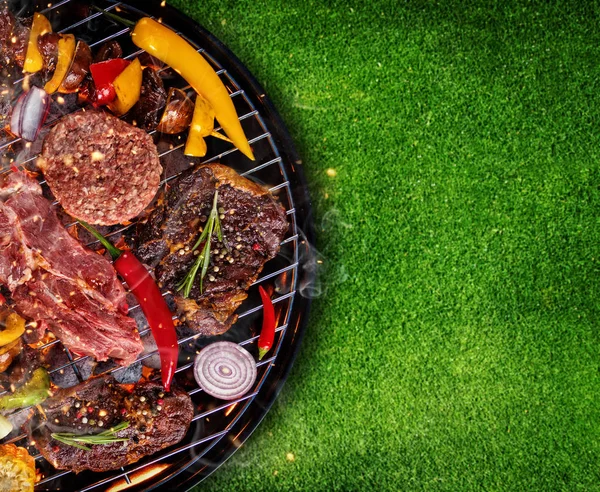 Vue de dessus de la viande fraîche et des légumes sur le gril placé sur l'herbe — Photo