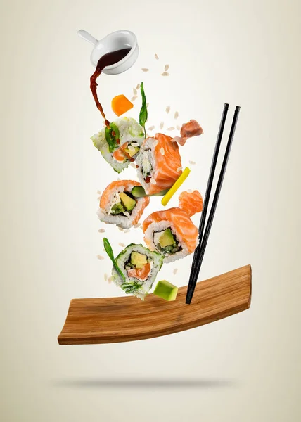 Pezzi di sushi volanti serviti su piastra di legno, separati su soft ba — Foto Stock