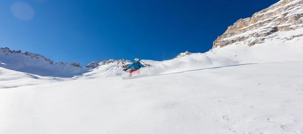 Ung man snowboardåkare kör neråt i pudersnö, Alpine mo — Stockfoto