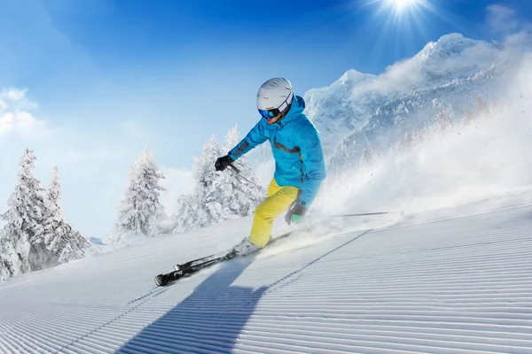 Junger Skifahrer läuft in alpiner Gebirgslandschaft den Hang hinunter — Stockfoto