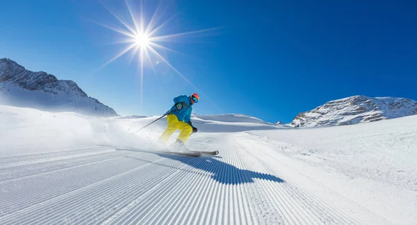 Jovem esquiador correndo pela encosta nas montanhas alpinas — Fotografia de Stock