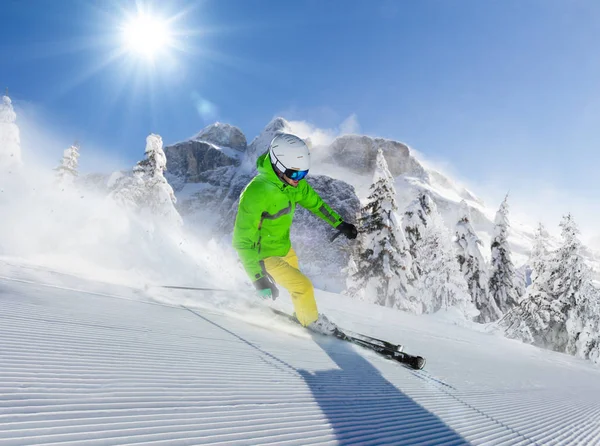 Junger Skifahrer läuft in alpiner Gebirgslandschaft den Hang hinunter — Stockfoto