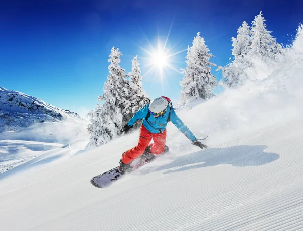 Mladý muž snowboardista běží ze svahu v alpských horách — Stock fotografie