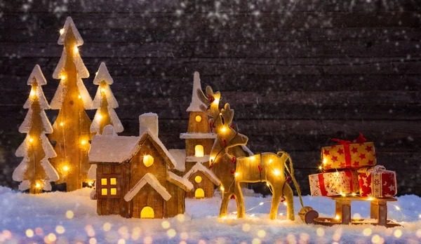Fundo de Natal com iluminado aldeia de madeira e alce — Fotografia de Stock