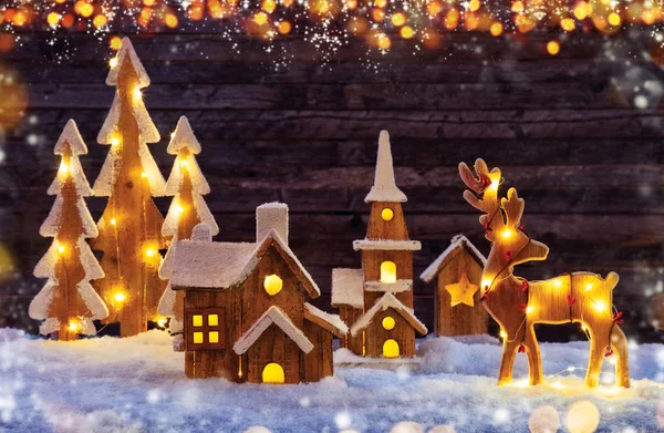 Christmas background with illuminated wooden village and moose — Stock Photo, Image