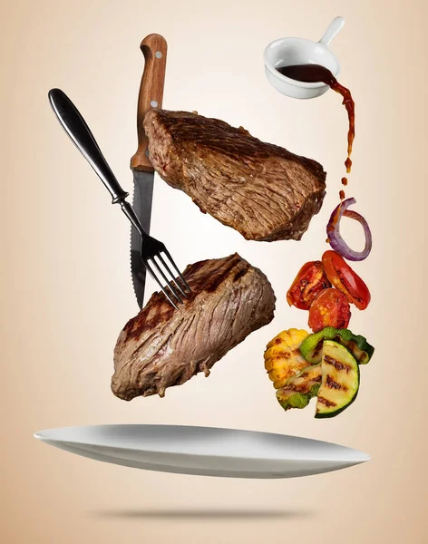 Flying beef steaks with grilled vegetable served on plate. — Stock Photo, Image