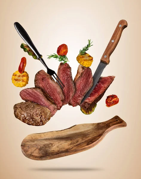 Flying beef steaks with grilled vegetable served on wooden cutti — Stock Photo, Image