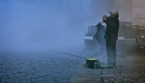 Two fishermen, trying to catch fish in early morning.