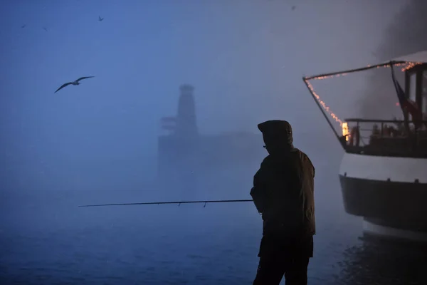 Alenefiskerens silhuett som prøver å fange fisk tidlig om morgenen – stockfoto