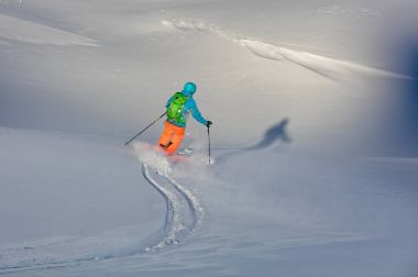 Genç freeride kayakçı yokuş aşağı çalışan taze toz karda