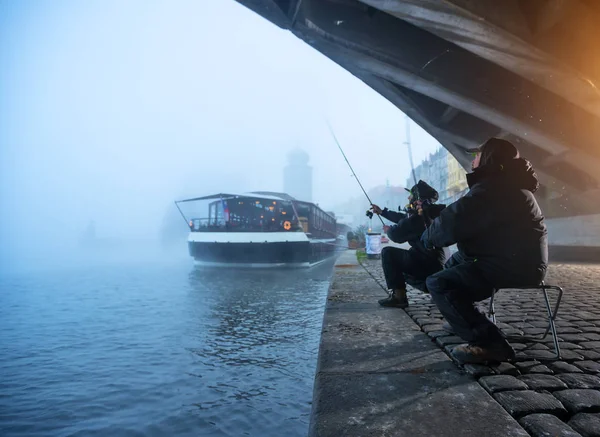 Двое рыбаков пытаются поймать рыбу в реке, рыбалка в городе . — стоковое фото