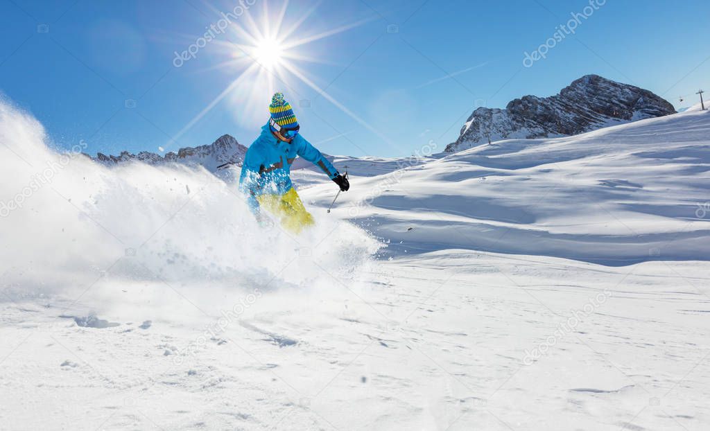 Young skier running downhill in beautiful Alpine landscape.