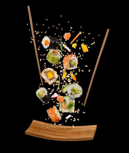 Летающие куски суши с деревянными палочками и тарелкой, изолировать — стоковое фото