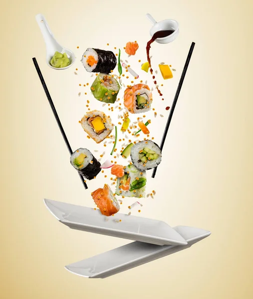 Létající kousky sushi s dřevěnými hůlkami, oddělené na beig — Stock fotografie