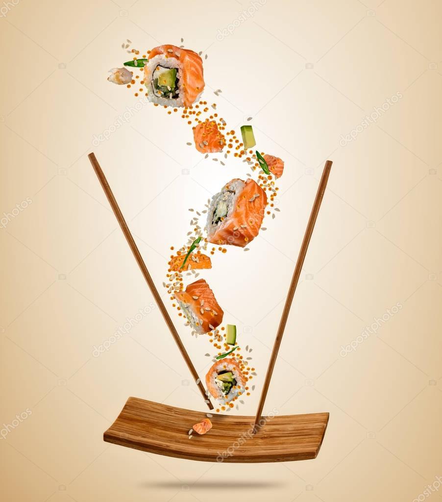 Flying pieces of salmon sushi with wooden chopsticks, separated 