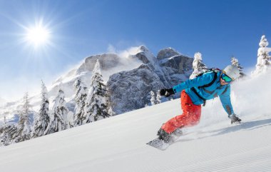 Yokuş aşağı Alpler'de çalışan genç adam snowboarder