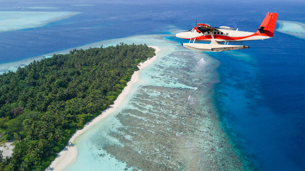 Seaplane flying above exotic iceland in Maldives.