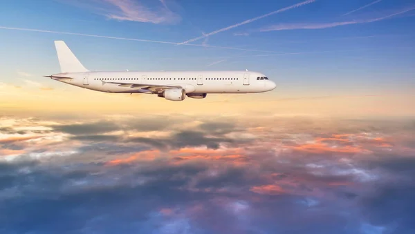 Avião jetliner voando acima das nuvens em luz do pôr do sol bonita . — Fotografia de Stock