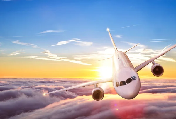 Airplane jetliner flying above clouds in beautiful sunset — Stock Photo, Image