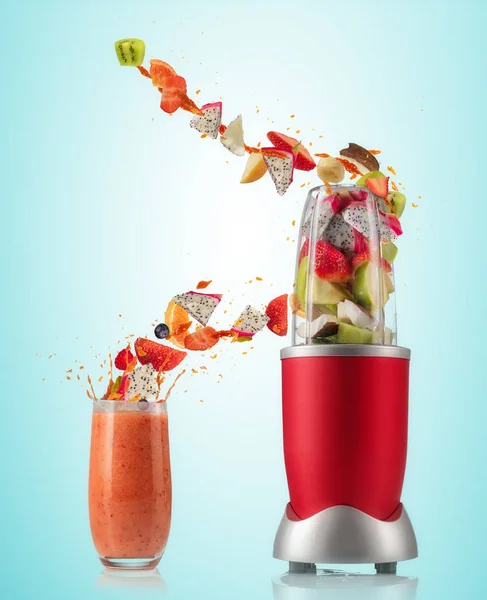 Змішувач та склянка з фруктовими літаючими інгредієнтами — стокове фото