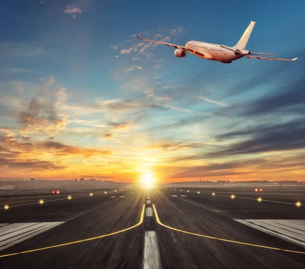 Avião comercial voando acima da pista sob a luz do pôr do sol . — Fotografia de Stock
