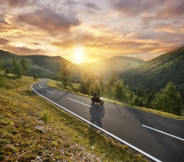 Motocycliste équitation dans les Alpes autrichiennes dans le magnifique coucher de soleil dramatique — Photo