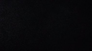 Siyah arka plan üzerine doğal organik toz parçacıkları. Işıltılı parçacıklar Bokeh ile. Ağır çekim.