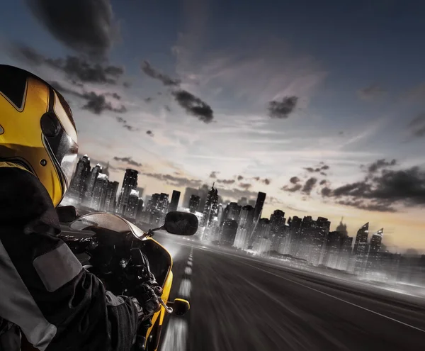 Суперспортивный мотоциклист, направляющийся к современному городу — стоковое фото