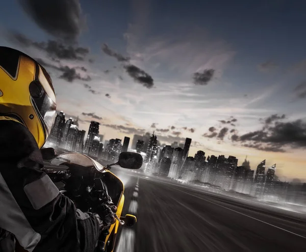 Supersport motorcycle rider heading to modern city skyline — Stock Photo, Image