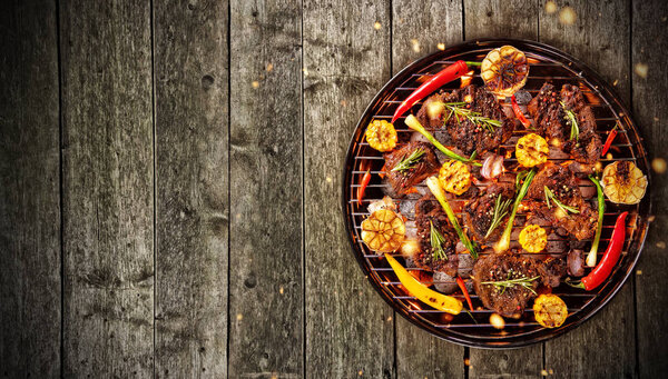 Вид сверху на свежее мясо и на гриль, помещенный на деревянную доску.
