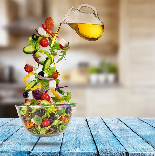 Vliegen plantaardige Griekse salade met gieten olijfolie van schotel. — Stockfoto