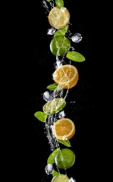 Plasterki limonki i cytryny wchodzących w plusk wody na czarnym tle — Zdjęcie stockowe