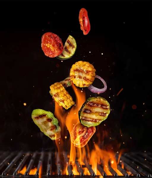 Flying pieces of vegetable from grill grid, isolated on black ba