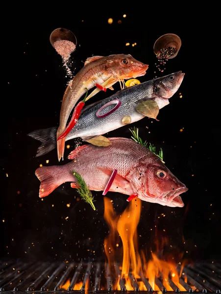 Fliegender roher ganzer Fisch vom Grillrost, isoliert auf schwarzem Backgro — Stockfoto