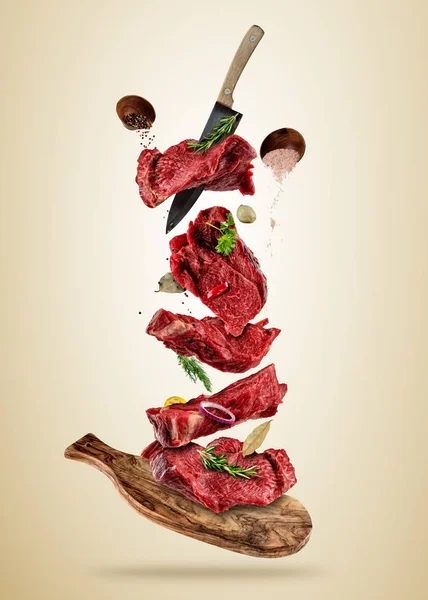 Flying pieces of raw beef steaks from cutting board — Stock Photo, Image