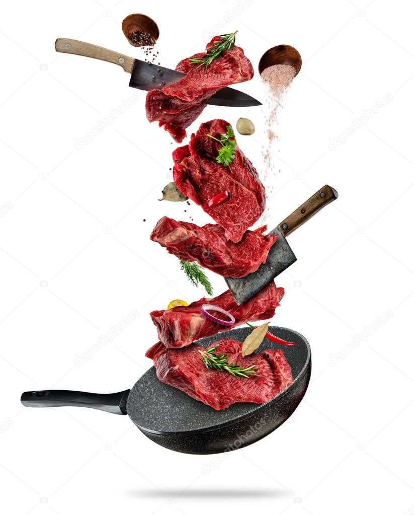 Flying pieces of beef steaks from pan on white background