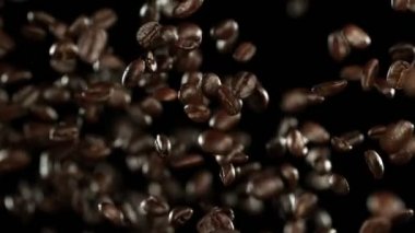 Uçan kahve çekirdekleri aşırı yavaş hareket ediyor. Yüksek hızlı sinema kamerası, 1000 fps..