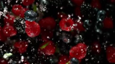 Çilekleri su sıçratan süper yavaş çekimde, siyah arka planda. Yüksek hızlı sinema kamerası, 1000 fps..