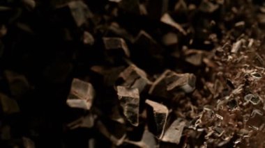 Çiğ çikolata parçalarından oluşan uçan bir grup süper yavaş çekim. Yüksek hızlı sinema kamerası, 1000fps.
