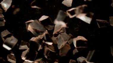 Süper yavaş çekimde, aşırı hız etkisiyle çiğ çikolata parçacıkları uçuyor. Yüksek hızlı sinema kamerası, 1000fps.