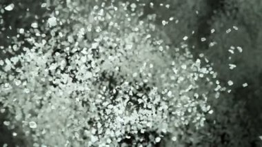 Siyah arkaplandaki taneli tuz parçalarını uçurmak için süper yavaş çekim. Yüksek hızlı sinema kamerası, 1000 fps.