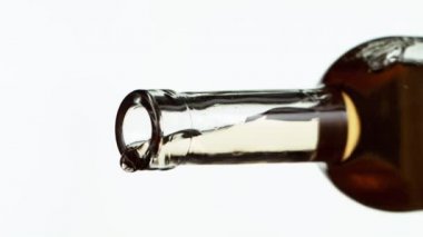 Beyaza izole edilmiş beyaz şarabın çok yavaş bir şekilde şişeden dökülmesi. Yüksek hızlı sinema kamerası, 1000 fps.