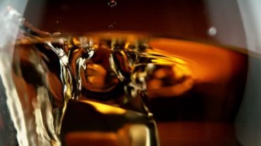 Süper makro çekimde buz küpünün viskiye dönüşmesi çok yavaş bir hareket. Yüksek hızlı sinema kamerası, 1000fps