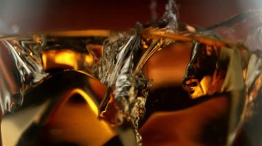 Süper makro çekimde buz küpünün viskiye dönüşmesi çok yavaş bir hareket. Yüksek hızlı sinema kamerası, 1000fps