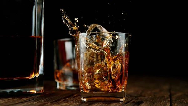 Splashing whiskey from glass with ice cubes inside — Stok Foto