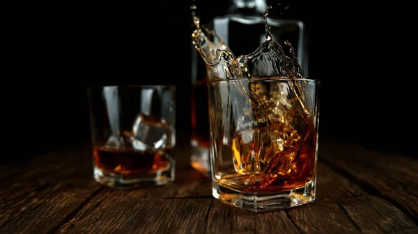 Spruzzare whisky dal vetro con cubetti di ghiaccio all'interno — Foto Stock